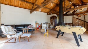 Een gezellige woonkamer met een bank, fauteuils, een tafelvoetbalspel en een hangstoel.