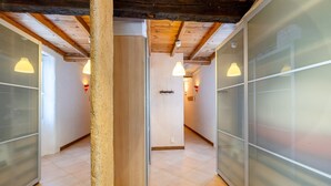 A hallway with wooden beams, frosted glass partitions, and pendant lighting.