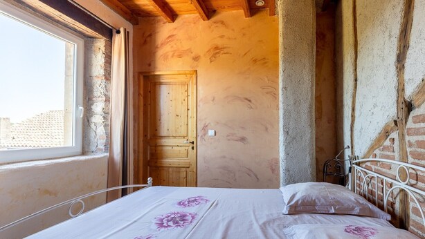 Een slaapkamer met een bed, een raam en een houten deur.