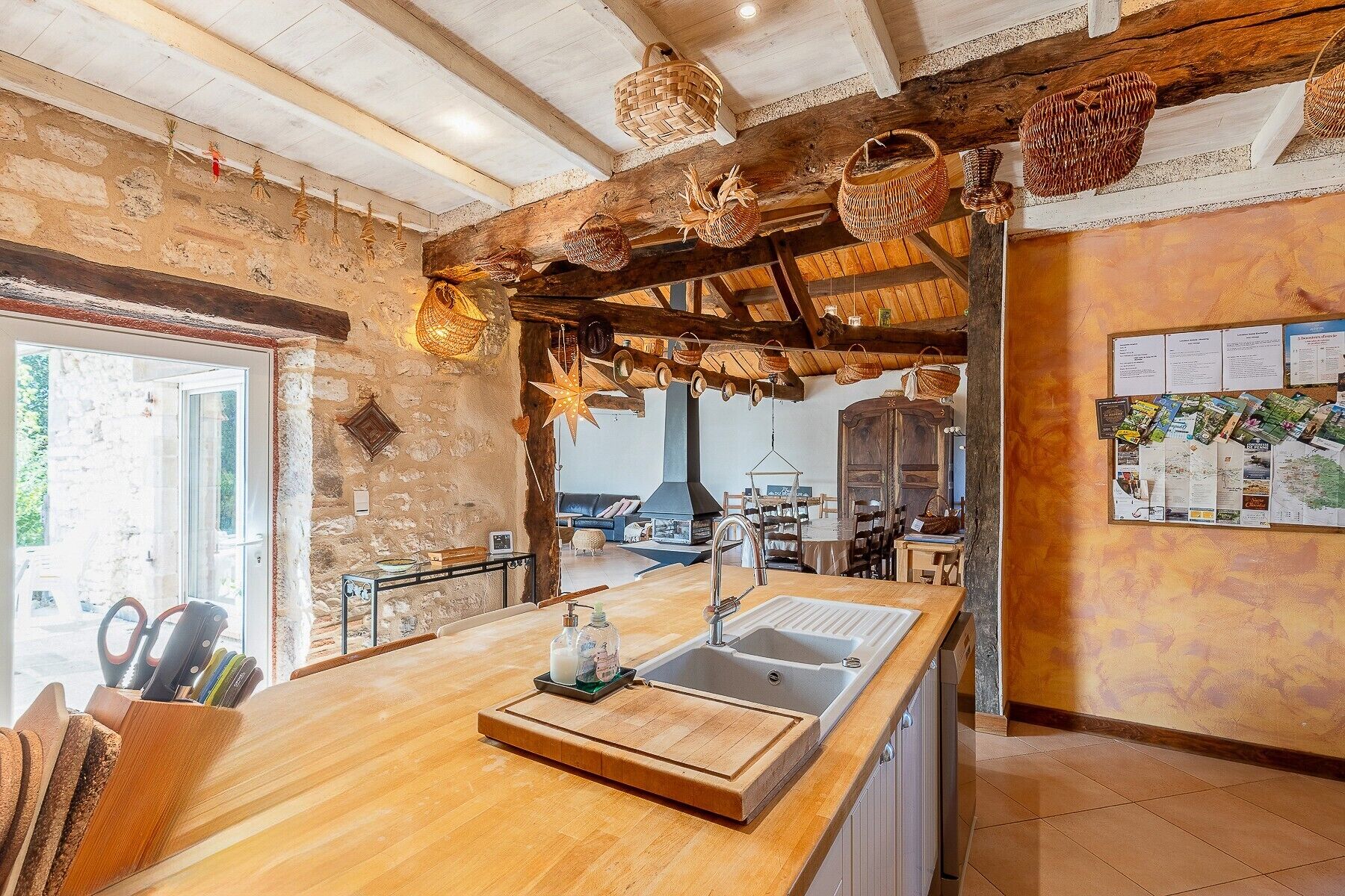 Cocina rústica con encimera de madera, un lavabo y cestas colgantes.