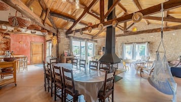 Un intérieur rustique avec une grande table ronde, des poutres en bois et un hamac suspendu.