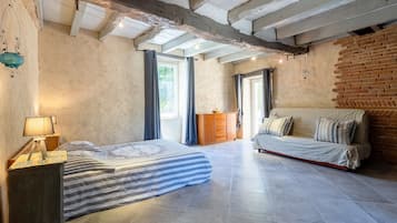 Une pièce comprenant un lit, un canapé, une armoire en bois et une lampe suspendue.