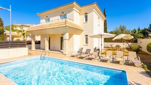 Un espace aménagé au bord de la piscine, comprenant une piscine, des chaises longues et un bâtiment doté d’un balcon.