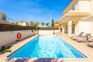 Une piscine équipée d’une bouée de sauvetage, de chaises longues et surplombée d’un ciel dégagé.