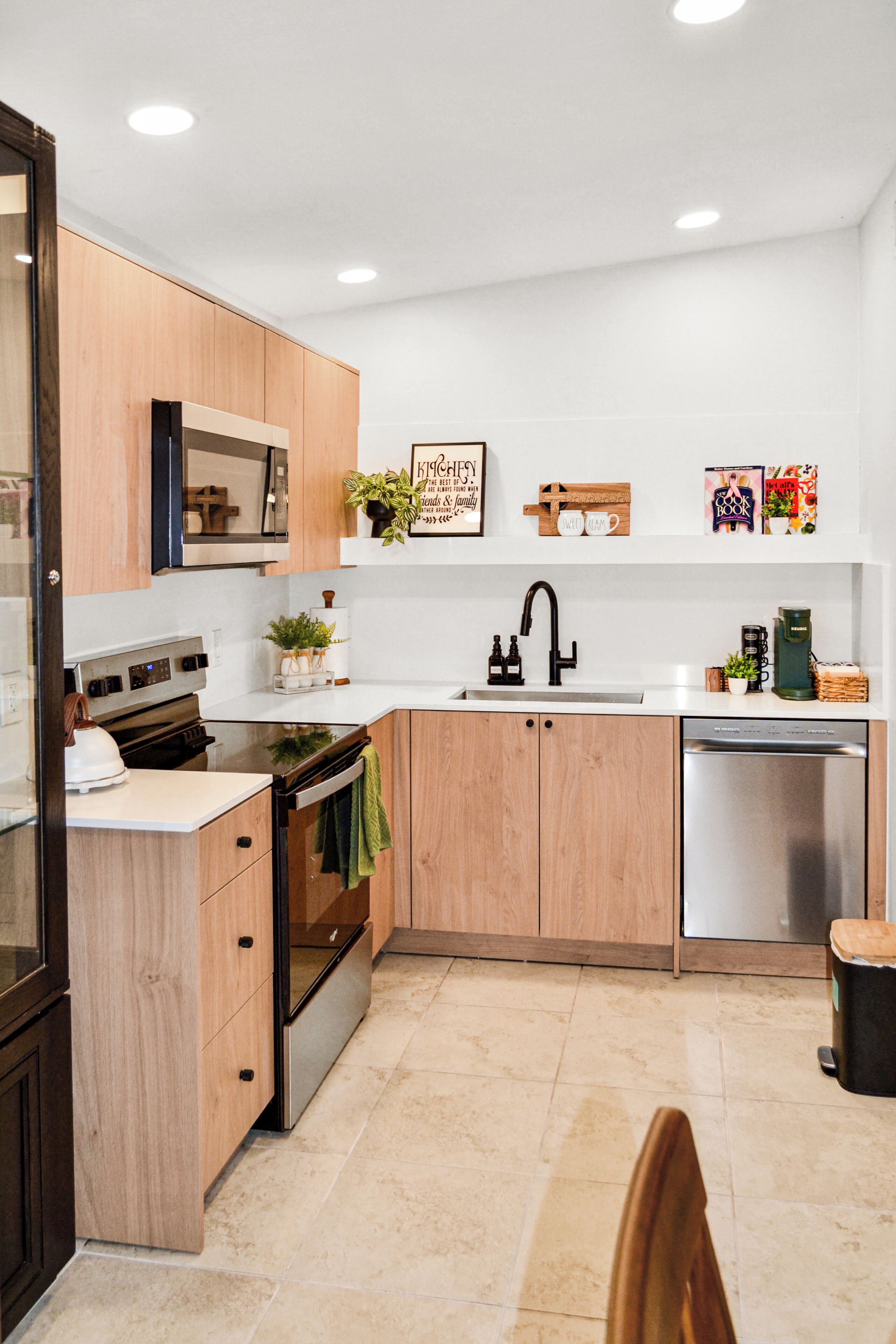 Una cocina moderna con armarios de madera, lavavajillas de acero inoxidable y horno empotrado.