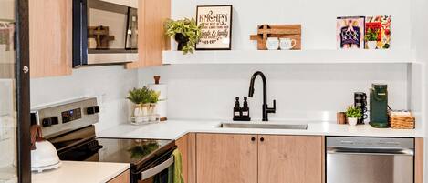 Una cocina moderna con armarios de madera, lavavajillas de acero inoxidable y horno empotrado.