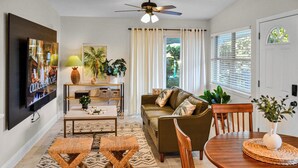 A living room with a sofa, coffee table, and a TV mounted on the wall. - Vibrant Cuban Style 3BR with AC near Beach & Downtown (Fort Myers)