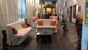 A hotel lobby with a central seating area, a bar, and artwork on the walls. - Fana Hotel (Dakar)