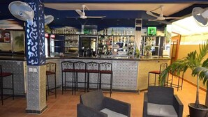 A bar area with seating, ceiling fans, and a bar counter stocked with bottles. - Fana Hotel (Dakar)