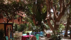 An outdoor patio area with stone flooring, potted plants, and outdoor seating. - Fana Hotel (Dakar)