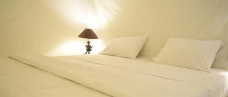 Een bed met wit beddengoed en een lamp met een bruine kap.