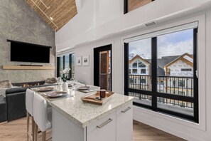 Een moderne keuken met een groot eiland, een flatscreen televisie en een open haard.