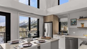 A modern kitchen with a central island, stainless steel appliances, and a view of mountains. - Elevation Hydeaway at Ascent (Canmore)