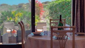 A dining table with chairs, a bottle, and plates, set against a backdrop of greenery and a clear sky. - Villa Gilda: Private Pool, Charm & Relax (Punta de Su Turrione)