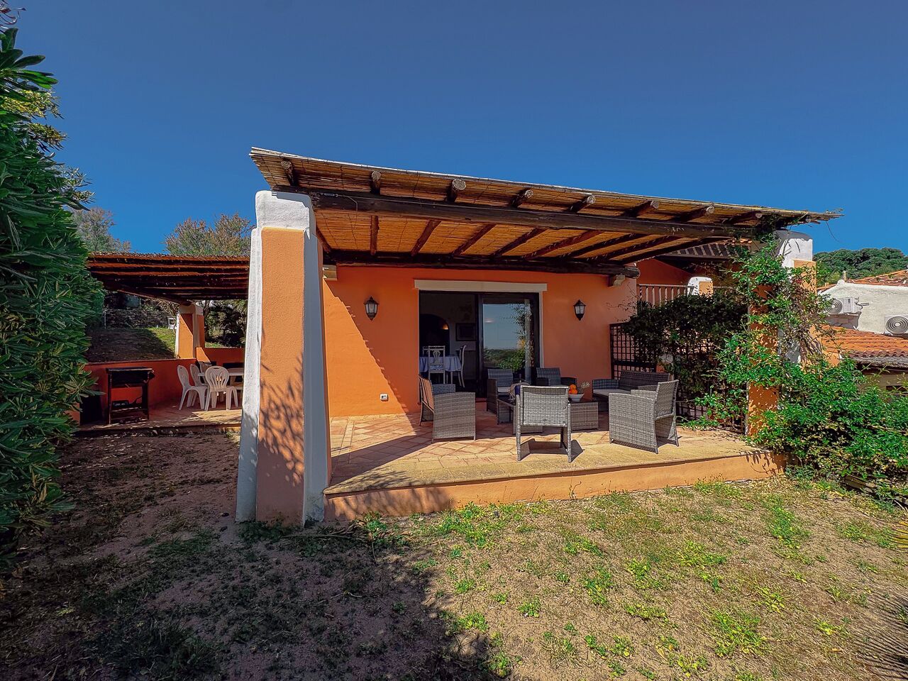 A house with an outdoor patio, a covered seating area, and a visible door leading to the interior.