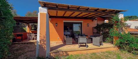 A house with an outdoor patio, a covered seating area, and a visible door leading to the interior.