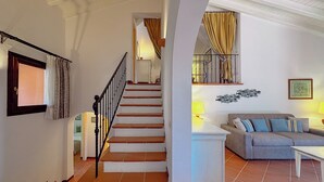 A staircase leading to a bedroom, a living room with a sofa and a lamp, and a dining area with a table. - Villa Gilda: Private Pool, Charm & Relax (Punta de Su Turrione)