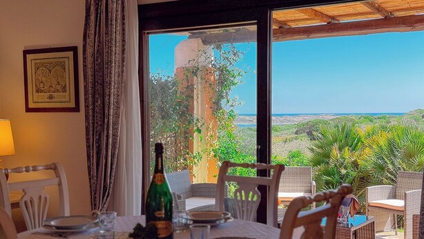 A dining table set for four with a bottle of champagne, plates, and cutlery. - Villa Gilda: Private Pool, Charm & Relax (Punta de Su Turrione)