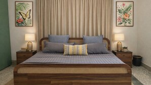 Une chambre à coucher avec un lit en bois, deux tables de chevet, une grande fenêtre avec des rideaux et deux tableaux floraux accrochés au mur.