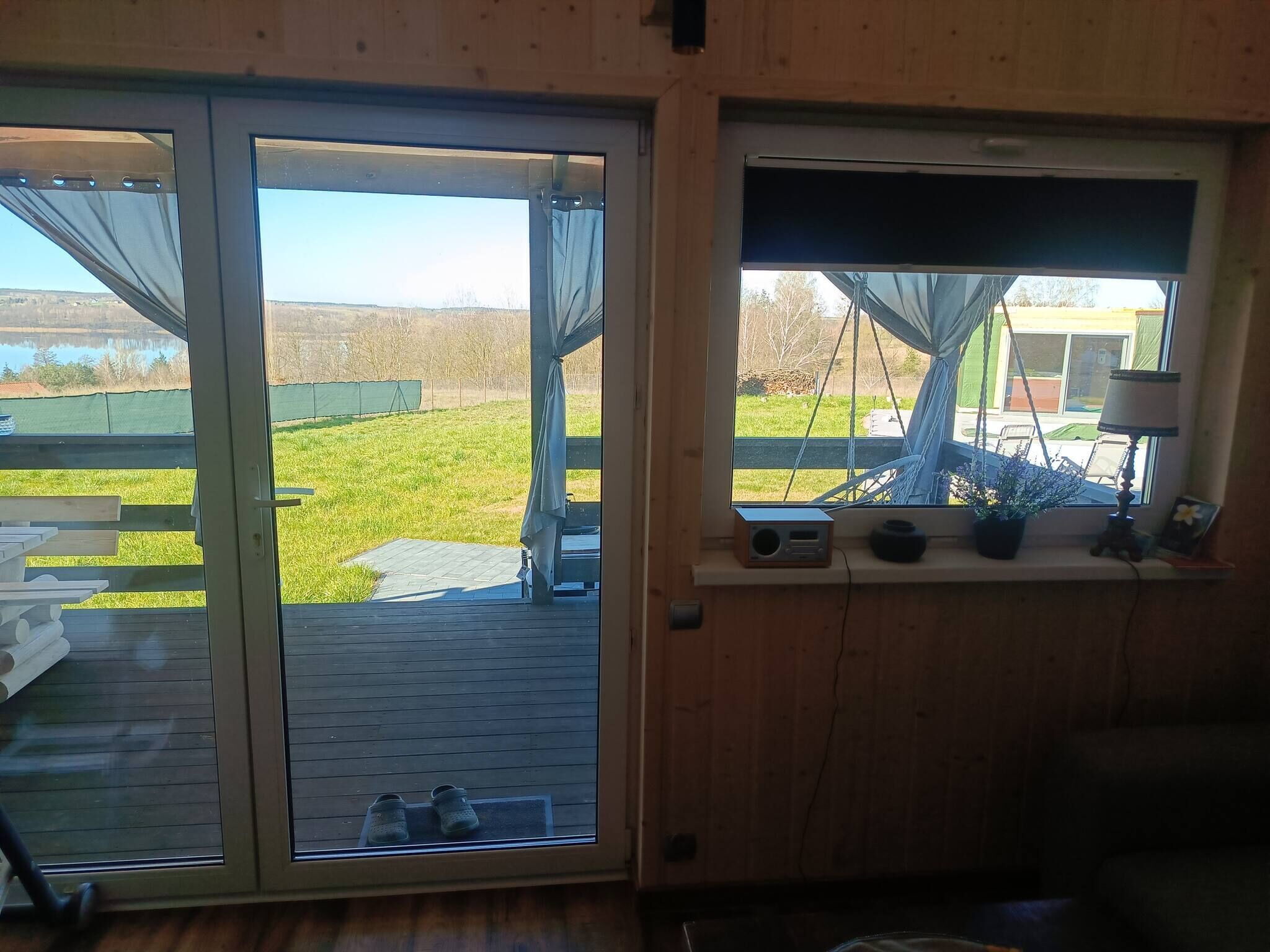 Una habitación con puerta de vidrio corrediza que da a un espacio exterior, un ventanal con vistas al exterior y suelo de madera.