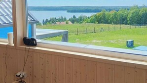 Une pièce dotée d’une grande fenêtre donnant sur un lac, d’un mur en bois et d’une petite table.