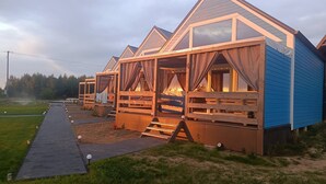 Une rangée de cabanes en bois dotées de grandes fenêtres et d’un porche abrité.