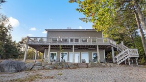 Un bâtiment à deux étages doté d’une terrasse en bois et d’un escalier menant à un deuxième niveau.