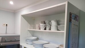 A kitchen with white shelves holding plates, cups, and a Zanker oven. - 1 room apartment with terrace, quietly situated on the edge of a field. (Remseck am Neckar)