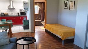 A compact living space with a kitchenette, a dining area, a single bed, and a small table. - 1 room apartment with terrace, quietly situated on the edge of a field. (Remseck am Neckar)