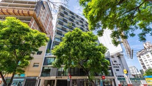 A multi-story building with a modern facade, a visible entrance, and a tree in front. - NUEVO Loft a 5 minutos de Puerto Madero 2C (Buenos Aires)