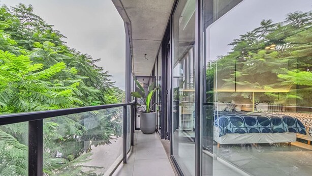 A balcony with glass railings, a potted plant, and a bed with a patterned bedspread. - NUEVO Loft a 5 minutos de Puerto Madero 2C (Buenos Aires)