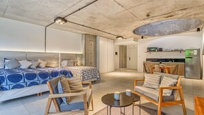 A modern hotel room with a large bed, a seating area with chairs and a table, a kitchenette, and a bathroom. - NUEVO Loft a 5 minutos de Puerto Madero 2C (Buenos Aires)