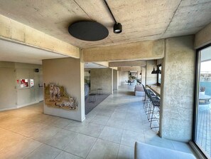 Un intérieur spacieux avec un plafond haut, des murs en béton et une longue salle à manger équipée de tables et de chaises.