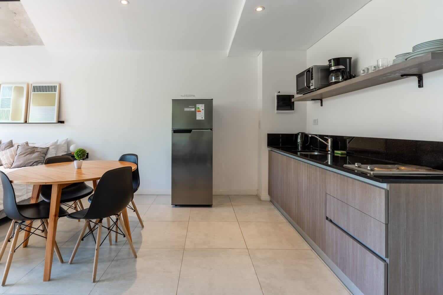Eine moderne Küche mit integrierter Kücheninsel, einem Kühlschrank und einem Essbereich mit Tisch und Stühlen.