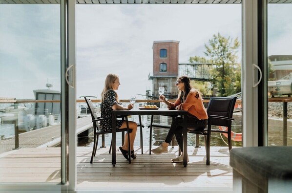 Two people dining at a table with a view of a dock and a building in the background.