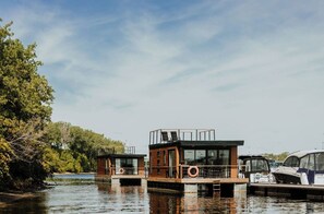 Una casa flotante con terraza, una pequeña cabaña y boyas salvavidas.