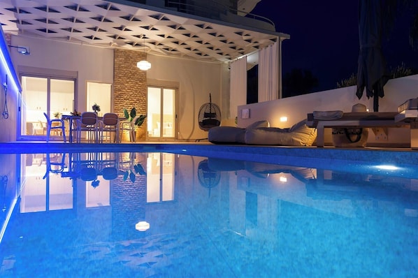 Una piscina de diseño moderno, un espacio de descanso techado al aire libre y vistas del edificio contiguo.