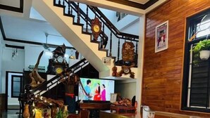 A spacious living area with a staircase, wooden benches, and a television. - DAI NOI SAPHIA HOMESTAY (Hue)