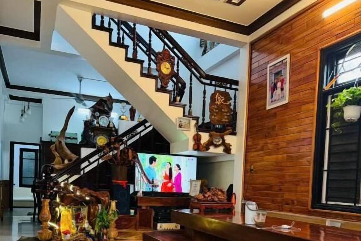 A spacious living area with a staircase, wooden benches, and a television.