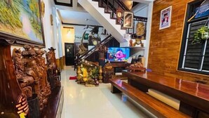 A spacious living area with a high ceiling, a staircase, and a television in the background. - DAI NOI SAPHIA HOMESTAY (Hue)