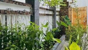 A garden with various plants, a stone wall, and a wooden fence. - DAI NOI SAPHIA HOMESTAY (Hue)