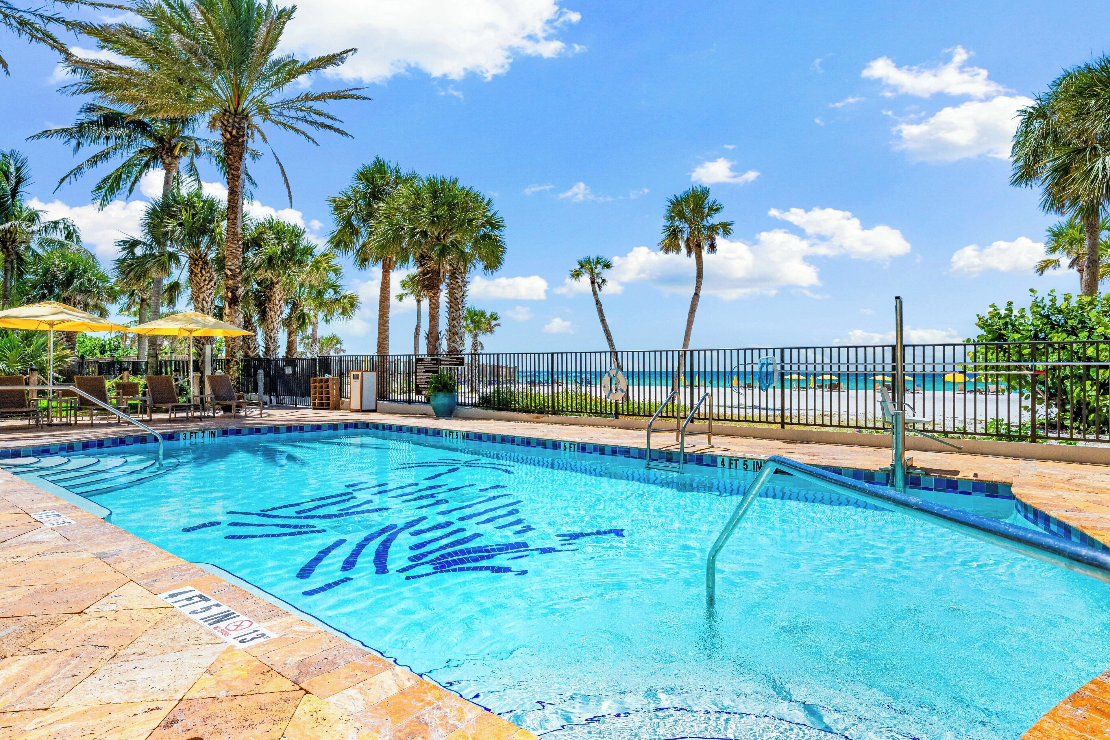 A swimming pool with palm trees and a clear sky.