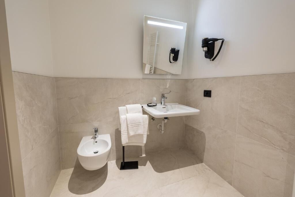 Un baño moderno con un bidé, un lavabo, un espejo y un perchero para toallas.