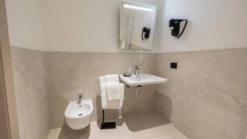 Un baño moderno con un bidé, un lavabo, un espejo y un perchero para toallas.