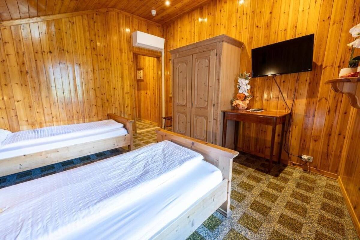 A wooden room with two beds, a TV, and a cabinet.