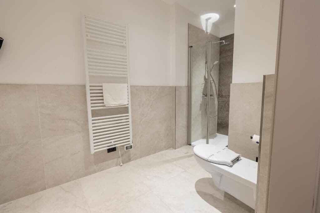 Un bagno moderno con il water, la doccia e un porta asciugamani.
