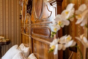 A wooden cabinet with a handle, a small table with items, and white flowers. - VILLAGGIO HOTEL AQUILA (Calliano)
