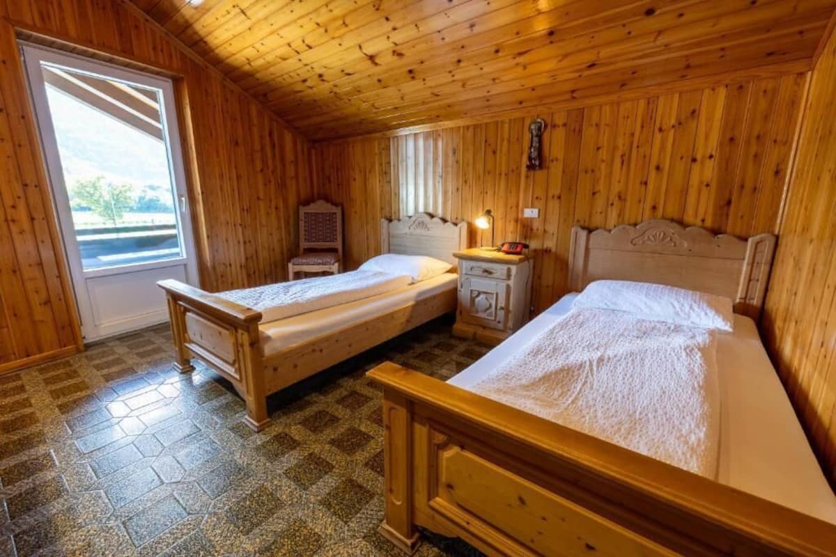A wooden room with two beds, a window, and a door.