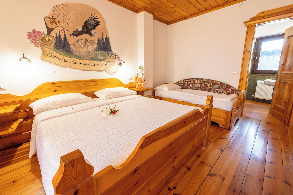A bedroom with two wooden beds, a mural on the wall, and a window with a view.