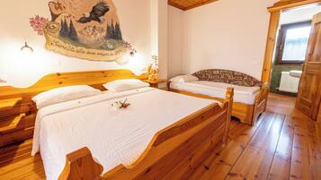 A bedroom with two wooden beds, a mural on the wall, and a window with a view.